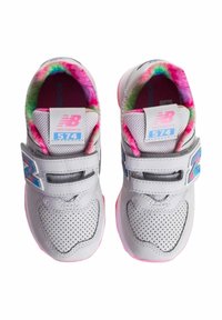 Sneaker grigio in pelle perforata, con accenti rosa e una fodera interna a tie-dye colorato. Presenta una cinghia in velcro e il logo New Balance.