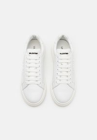 Witte leren sneakers met ronde neus, platte veters en een overgrote rubberen zool. Heeft branding op de tong en zijkant. Glad oppervlak.