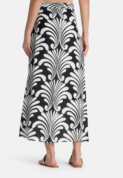 Zwart-wit gestreepte maxi rok met een vloeiende design, gekenmerkt door een gedurfd floral motief en een soepele textuur. Platte tailleband en sandalen zichtbaar.