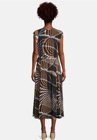 Svart och brunmönstrad midiklänning med korta ärmar, elastisk midja och virvlande geometriska mönster. Slät textur, flytande silhuett.