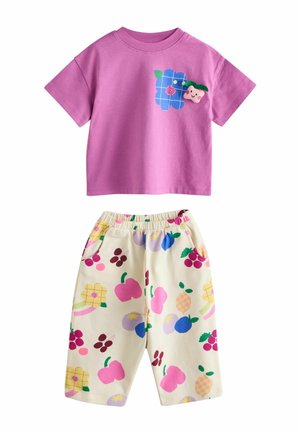 Růžové bavlněné tričko s krátkým rukávem s modrou grafikou květin a ovoce; odpovídající krémové kraťasy s barevnými vzory ovoce a elastickým pasem.