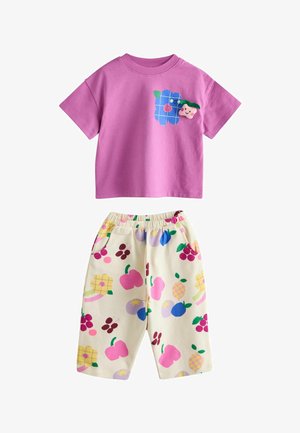 Różowa bawełniana koszulka z krótkim rękawem z niebieską grafiką kwiatów i owoców; pasujące kremowe szorty z kolorowymi wzorami owoców i elastycznym pasem.