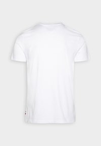 Camiseta blanca de manga corta, hecha de algodón, con un diseño de escote en V y un ligero bajo trasero. Sin patrones ni acentos visibles.