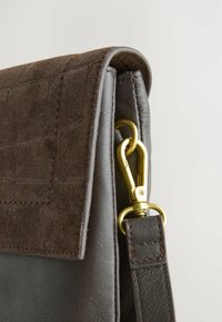 Brun lædertaske med en suedeflap i krokodilleskinds mønster, guldfarvede hardware detaljer og en syet læderrem.