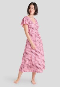 Vestido envolvente rosa con patrones de diamantes en blanco, mangas cortas con vuelo, escote en V y un cinturón de lazo, que llega hasta medio pantorrilla.