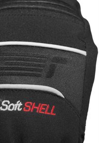 Sort softshell-stof med hvide accenter. Udstyret med broderet "Soft SHELL" i rødt, med markante teksturerede mønstre og glatte linjer.