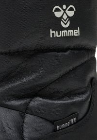 Svarta isolerade kängor med en strukturerad yta, med en framträdande hummel-logotyp och en vattentät hummelTEX-tag på sidan.