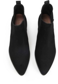 Botas negras hasta el tobillo con punta afilada y textura suave similar al ante, con recortes laterales y una pequeña lengüeta en la parte posterior.