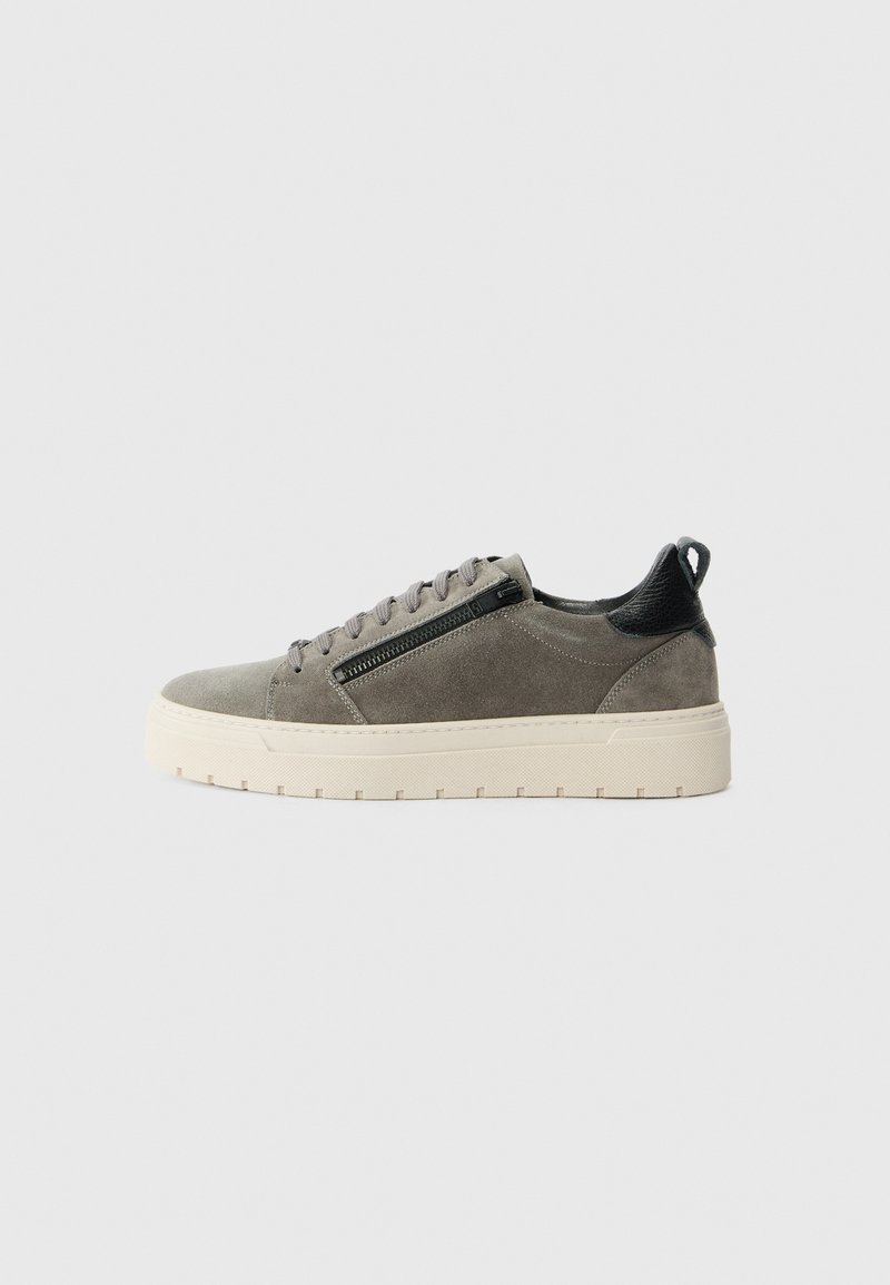 Lave-grå semsket sneaker med sort hælflik, sidelukning med lynlås, snørebånd og beige tyk gummisål på en lys baggrund.