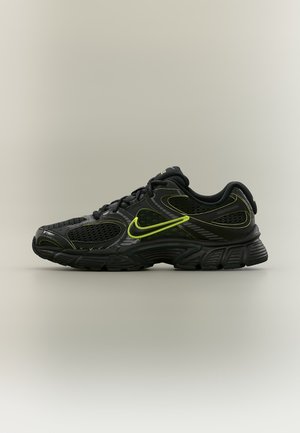 Черна маратонка Nike с неоново зелени акценти, мрежести панели и дебело текстурирано ходило, показана отстрани на неутрален фон.