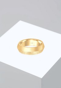 Guld ring med en struktureret overflade og polerede kanter. Sekskantet form, mærket med "925" indeni, præsenteret på en hvid pedestal.