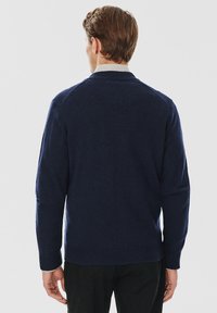 Granatowy sweter z dzianiny z okrągłym dekoltem, ściągaczem u dołu i długimi rękawami. Miękka struktura i klasyczny krój, pokazany z tyłu.