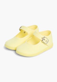 Zapatos Mary Jane de lona amarillos con punta redondeada, suela de goma plana y una correa ajustable con un hebilla de plata.