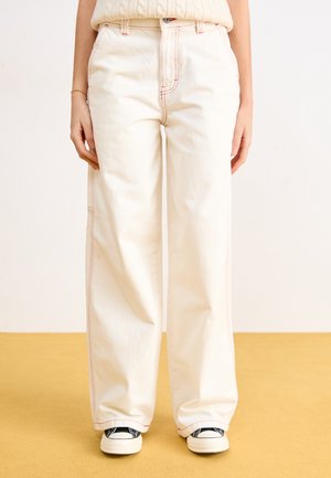 Wide-leg, off-white pants in lightweight fabric with contrasting red stitching. Front pockets and a classic button closure enhance design.