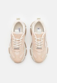 Zapatillas de malla rosa con acentos blancos, con una suela gruesa, patrones texturizados y cordones resistentes. Punta redondeada y lengüeta con tiradores.