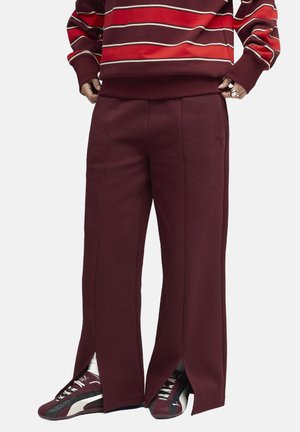 Maroon wide-leg pants with side splits, made of soft fabric. Paired with maroon and black sneakers featuring white accents.