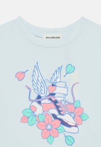 Ανοιχτό μπλε μπλουζάκι με γραφικό από πατίνια ρόλερ με φτερά, περιτριγυρισμένα από ροζ λουλούδια και καρδιές, με λαμπερά και γυαλιστερά στοιχεία.