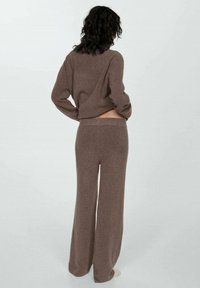 Brunt stickad loungewear-set som består av en kort tröja med långa ärmar och högmidjade vida byxor. Mjuk textur med avslappnad passform.
