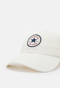 Cappellino da baseball in cotone bianco con visiera curva, dotato di un logo ricamato circolare in blu navy e rosso che include una stella e del testo.