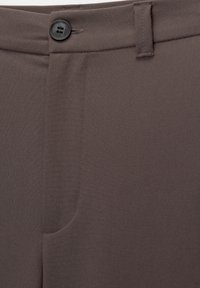 Pantalon marron en tissu tissé lisse, avec une fermeture à un bouton, des poches latérales et des coutures soignées.