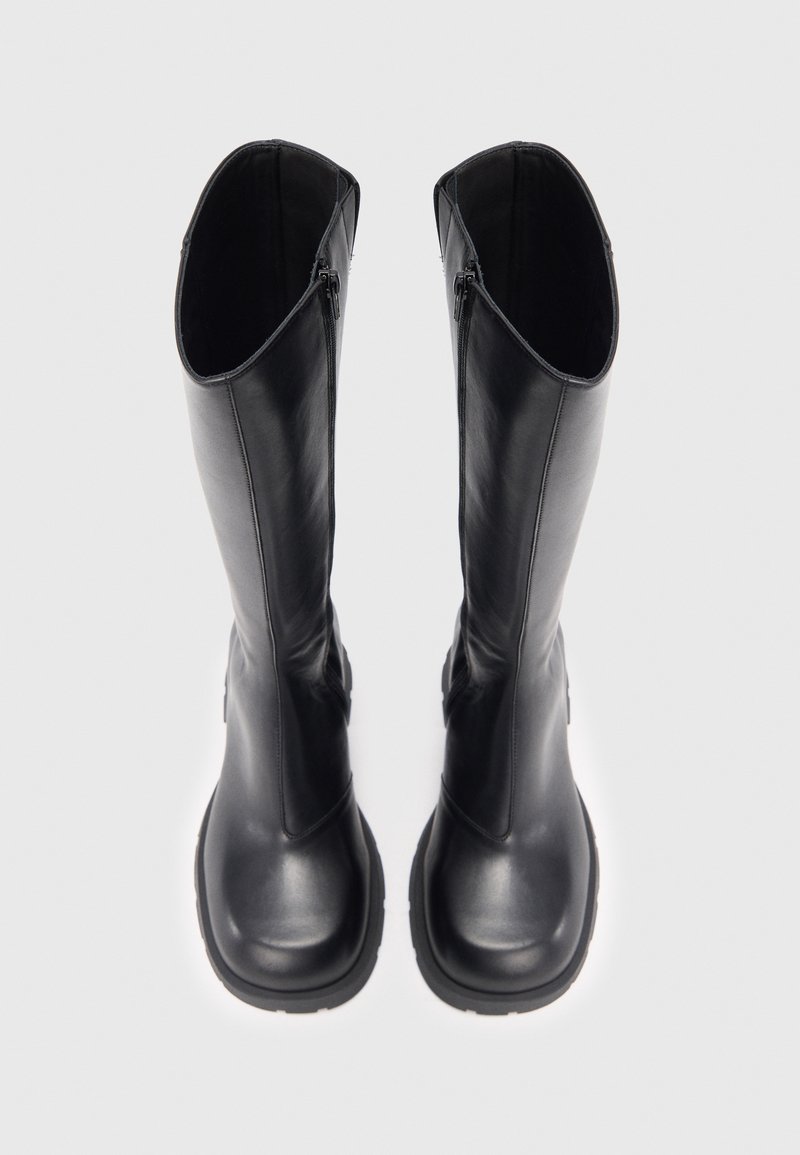 Sorte knæhøje støvler med glat læderfinish, rund tå og tydelig syning. Har sidelommer med lynlås for nem påtagning. Strukturerede såler.