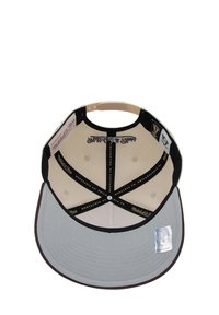 Baseball cap with a grey brim, black underside, beige crown, and interior markings. Features a branded label and stitching details.