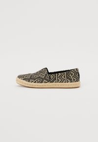 Svart og kremmønstret espadrille med vevd tekstiloverdel og naturlig ropesåle, med flat design og slip-on stil.