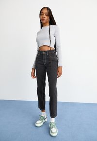 Pelēka ribota garām piedurknēm īsā blūze, apvienota ar augsto vidukli melnajām džinsām un zaļi akcentētām kedām. Gludas tekstūras un šaurs piegriezums.