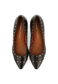 Zapatos de cuero negro con punta afilada y acentos de tachuelas doradas a lo largo de los lados, con una textura suave. El interior cuenta con un forro en tonos marrones.