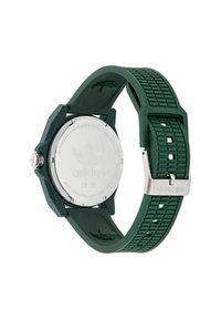 Grön klocka med silikonarmband och texturerad yta samt baksida i rostfritt stål. Rund design med Adidas-logotyp och silverfärgad spänne.