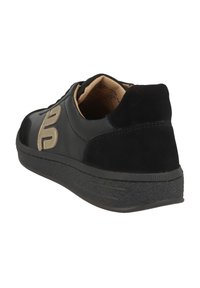 Zapatilla negra hecha de cuero con un talón de gamuza, que cuenta con una suela de goma texturizada, un detalle del logotipo en beige y un interior acolchado.