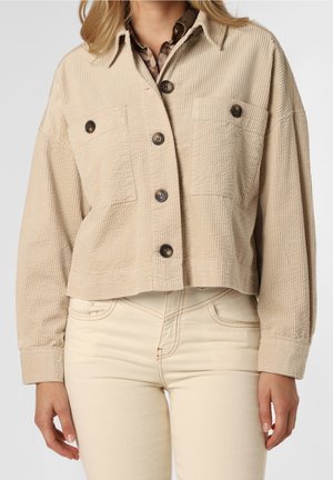 Veste en velours côtelé beige au design court, avec deux poches avant et des boutons marron. Manches longues avec des poignets boutonnés.