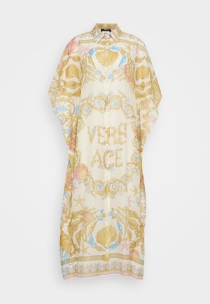 Kaftan leve, de cor creme, com um padrão de conchas e corais; apresenta a palavra "VERSACE" em dourado no centro, com botões.