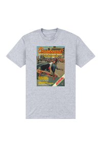 Šedé tričko s krátkým rukávem, které zobrazuje grafiku obálky vintage skateboardového časopisu, složitý text a barevné ilustrace.