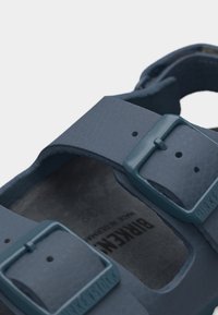 Κοντινό πλάνο από μπλε λουριά σανδαλιού Birkenstock με ταίριασμα αγκράφες και υφασμένο πέλμα στο εσωτερικό.