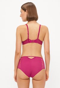 Magenta lingerie set met een beha met verstelbare schouderbanden en een haaksluiting, gecombineerd met hoge slipjes met kanten accenten.