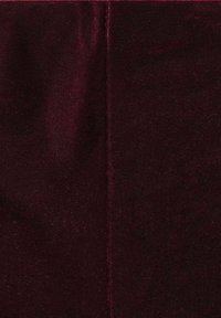Close-up of soft, dark burgundy velvet fabric with a visible vertical seam down the center.