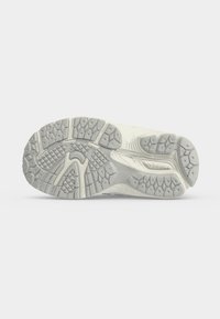 Σόλα γκρι και λευκού αθλητικού παπουτσιού New Balance με υφή λαβής και ορατό λογότυπο της μάρκας στην περιοχή της καμάρας.