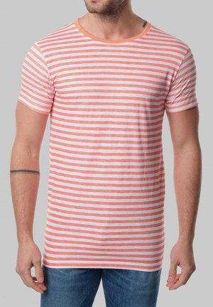 T-shirt rayé avec des bandes horizontales corail et blanches, col rond, manches courtes, en tissu doux, associé à un jean bleu.