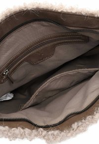 Interno di una borsa in pelle marrone con rifiniture in pelliccia beige, dotato di una tasca con zip e una fodera in tessuto liscio. Due ulteriori tasche aperte visibili.