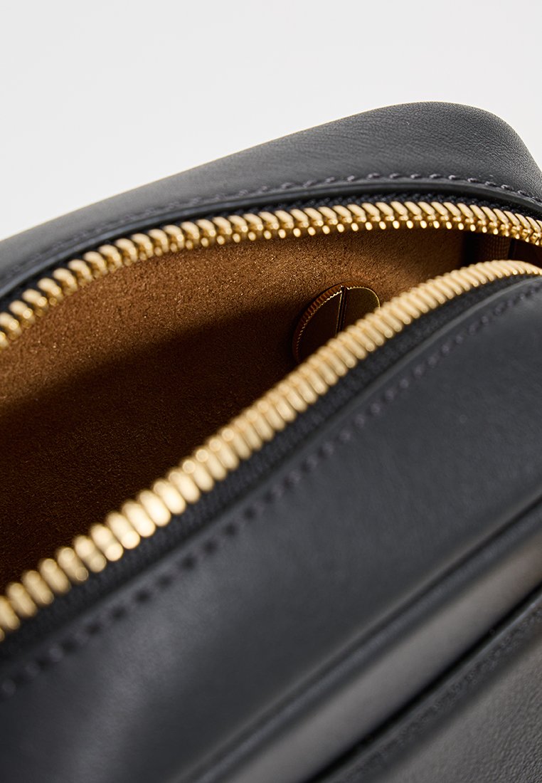 Schwarze Ledertasche mit goldenem Reißverschluss. Sie verfügt über ein weiches braunes Futter und eine runde Tasche. Der Reißverschluss ist auffällig und funktional.