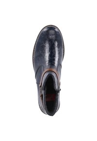 Bottine bleu marine en cuir brillant à texture craquelée, avec une lanière accentuée marron et une doublure intérieure pelucheuse.