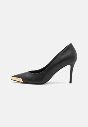 Chaussure à talon haut en cuir noir avec un bout pointu et un accent en cap métallique doré à l'avant. Présente une silhouette élégante et un talon stiletto fin.