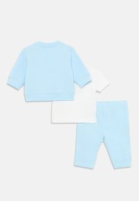Ensemble pour enfants en deux pièces comprenant un sweat-shirt bleu clair et un pantalon assorti, avec un t-shirt à manches courtes blanc. Matériau en coton doux.