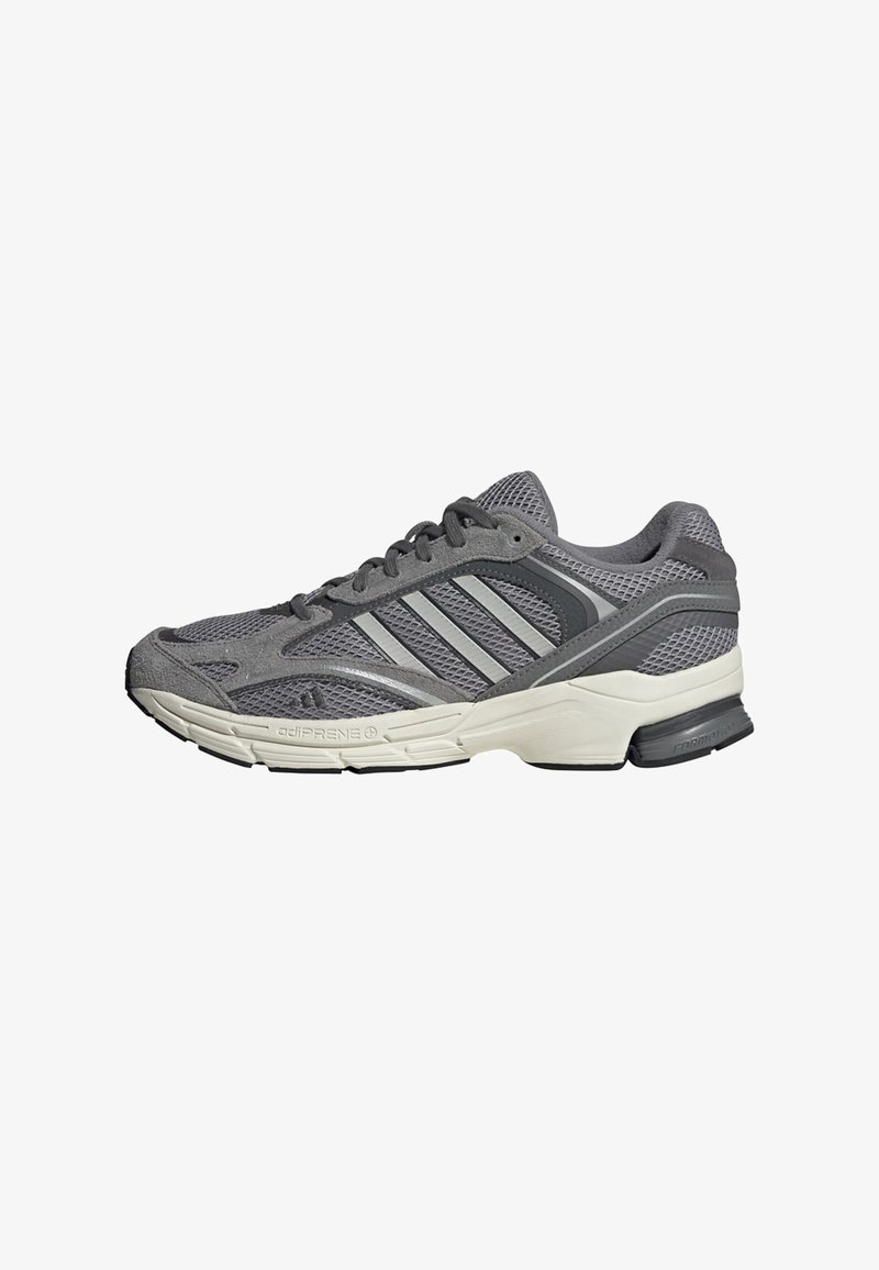 Baskets de sport gris et noir avec semelle blanche, empeigne en mesh et suède, fermeture à lacets et trois bandes diagonales sur le côté.