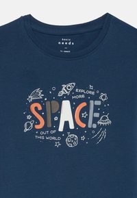T-shirt in cotone blu navy con scollatura rotonda, caratterizzato da un design grafico di razzi, pianeti e il testo "ESPLORA PIÙ SPAZIO."