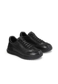 Zapatillas negras que combinan materiales de cuero suave y ante, con puntera redondeada, sistema de cordones y suela de goma gruesa para mayor agarre.