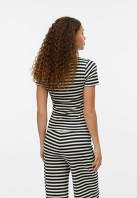 Stribet jumpsuit i marineblå og creme, korte ærmer, tætsiddende design, blødt stof, synlige sømme og en scoop-udskæring.