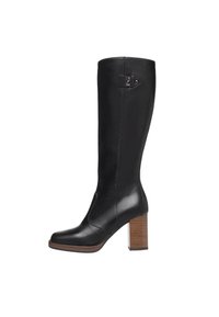 Botte haute en cuir noir avec talon bloc en bois empilé et petit logo métallique près du haut sur le côté extérieur.