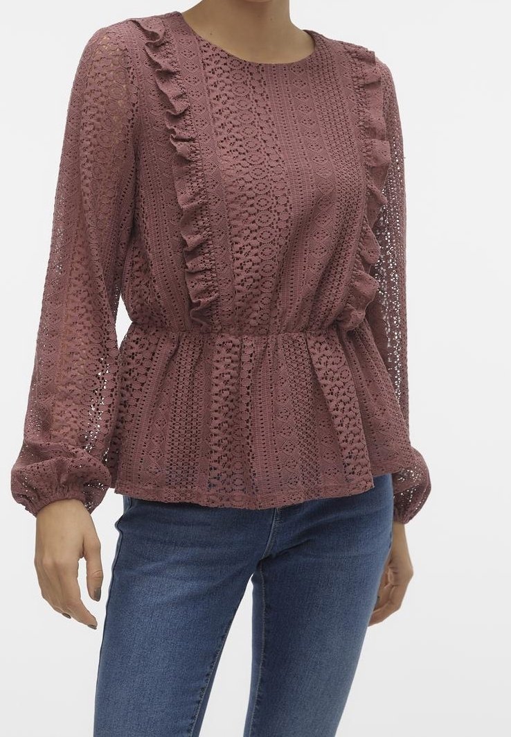 Femme portant un chemisier en dentelle mauve à manches longues avec des détails à volants et un jean bleu, visible du cou aux hanches sur fond blanc.